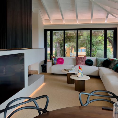 Sala de estar con sofá capitoné, cojines estampados y acuario digital integrado, en casa reformada del Maresme por Prada’s Design.