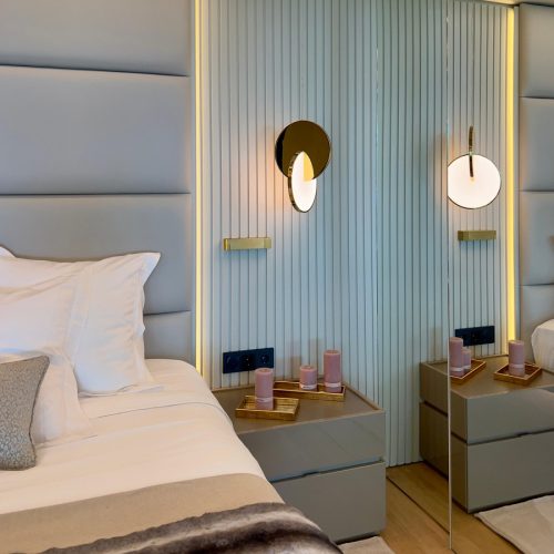 Iluminación de diseño en dormitorio principal en vivienda reformada del Maresme con cama flotante de LAGO y cabezal capitonado. Interiorismo de Prada’s Design.